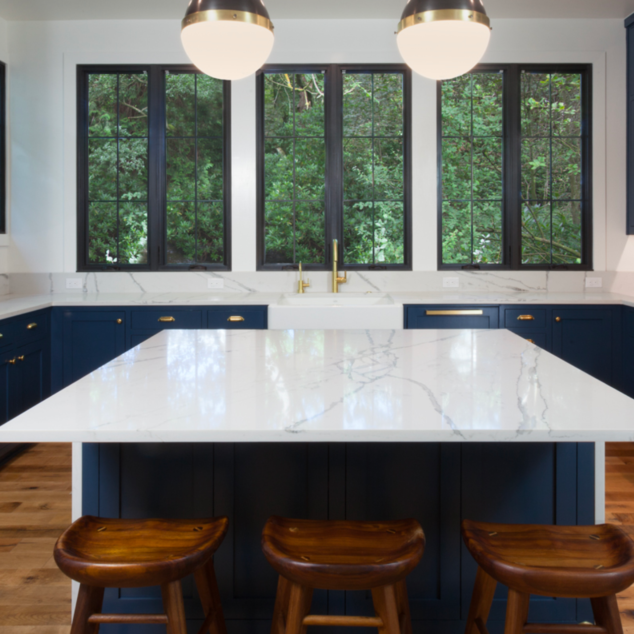 White quartz countertops and white quartz island with navy blue cabinets and gold hardware in Austin, Texas