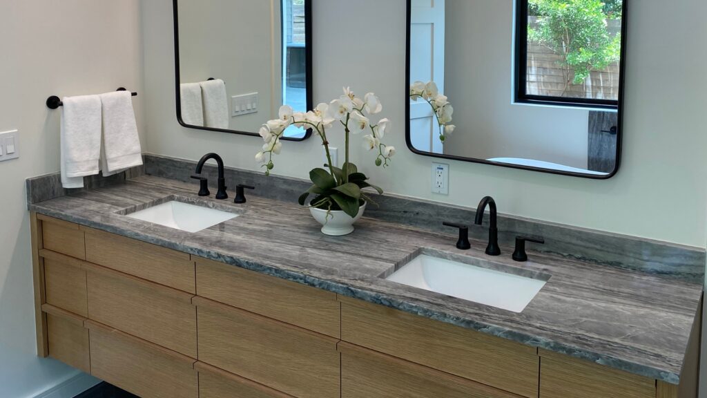 Toor-Countertops-Austin-Bathroom-Design- A floating grey marble vanity with a double sink and sleek wood cabinets by Toor Countertops in Austin, Texas.